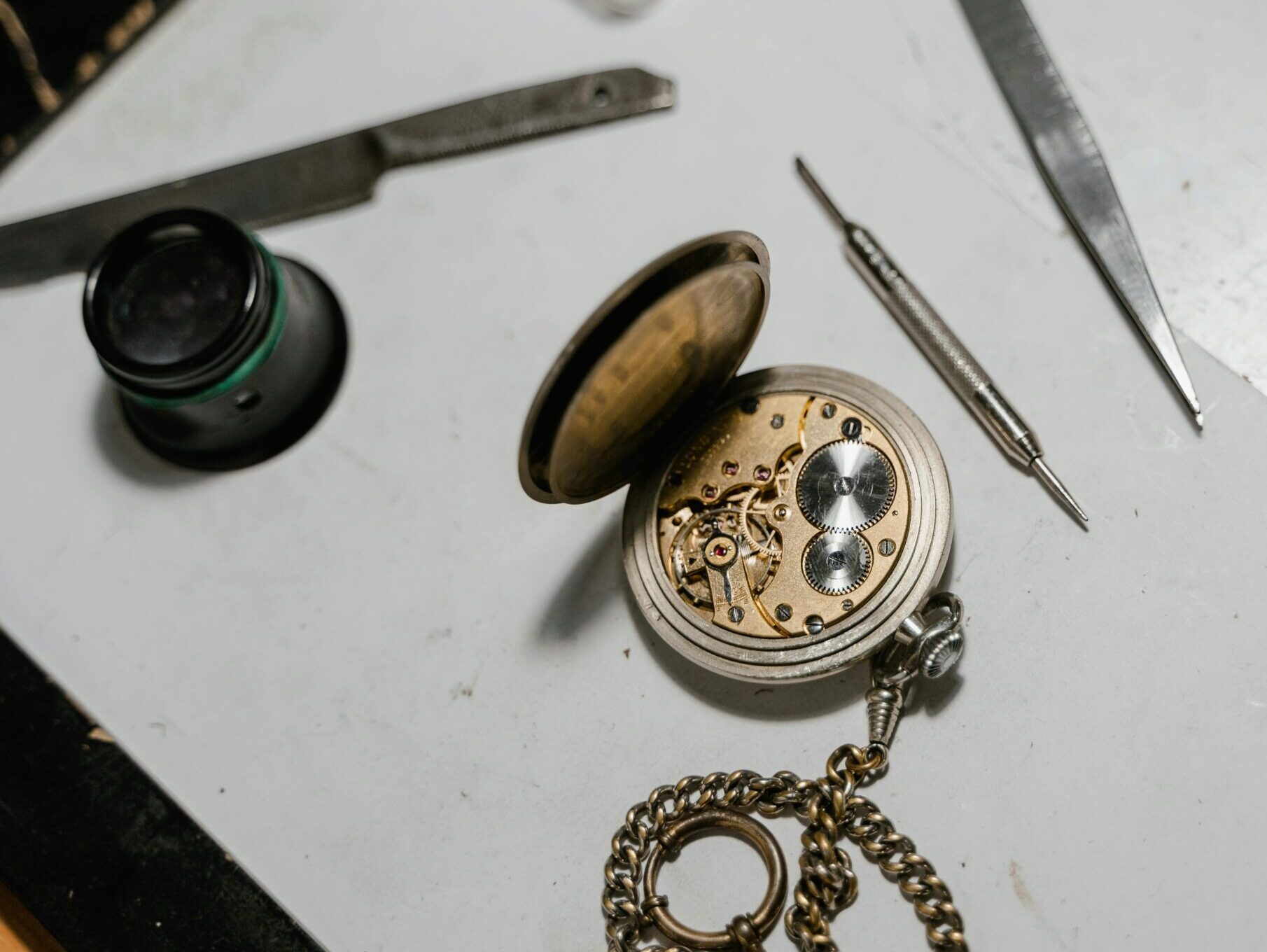 Detailed view of a vintage pocket watch with repair tools, showcasing precision craftsmanship.